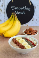 Chocolate smoothie bowl topped with banana, goji berry, pecan nuts, coconut chips and chia seeds
