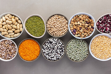 Different types of legumes in bowls, green and yellow peas, chickpeas and peanuts, colored beans and lentils, mung beans and beans, top view