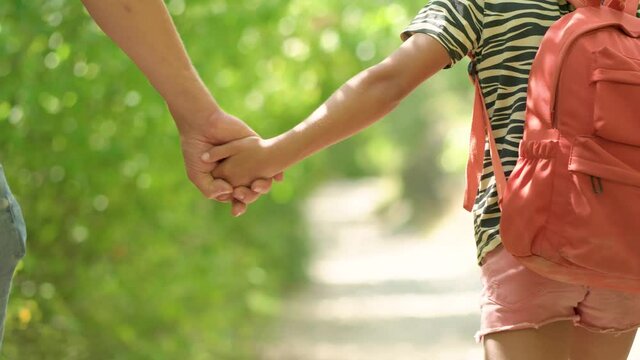 Man walking with girl. Travel lifestyle concept adventure outdoor summer vacations. Happy family hiking in the countryside. Father and daughter walking in the forest. Close up view of hands together.
