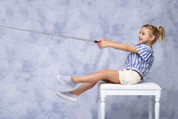 A cute little girl imitates fishing with a fishing rod.