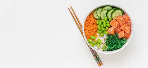 Poké bowl with fresh salmon, rice, chukka salad, edamame beans, carrots and cucumber. Bowl of healthy food on white background