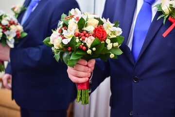 The groom with a bouquet of wedding flowers stands near the mirror and is reflected in it. Flowers for the bride. close-up without a face.
