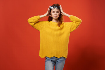 woman in yellow sweater holding her head lifestyle red background