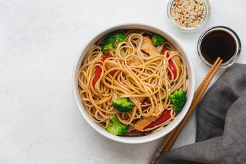 Egg noodles with broccoli and red bell peppers in bowl. Stir fry noodles with soy sauce and sesame seeds 