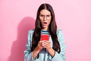 Photo of unhappy young woman hold smartphone dislike post reaction isolated on pink color background
