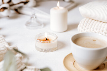 Details of still life in the home interior of living room. Cup of coffee, cotton, book, candle, sweater. Moody. Cosy autumn winter concept on white background. Decoration.