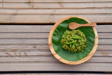 Sambal Cabe Ijo. Traditional Indonesian green chili paste on banana leaf, place on wooden background