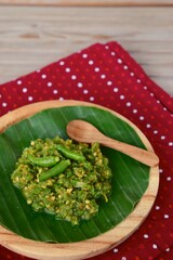 Sambal Cabe Ijo. Traditional Indonesian green chili paste on banana leaf, place on wooden background