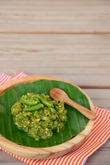 Sambal Cabe Ijo. Traditional Indonesian green chili paste on banana leaf, place on wooden background