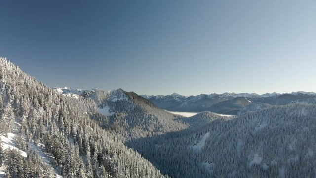 Drone Flying Fast by Snowy Cascade Mountains on Crisp Winter Day