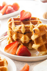 Delicious breakfast. Belgian waffles with honey and strawberries. Cup of tea white wooden background, top view.