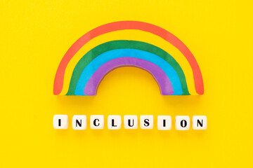 Inclusion text yellow background. Inclusive social concept. Wooden blocks, top view.