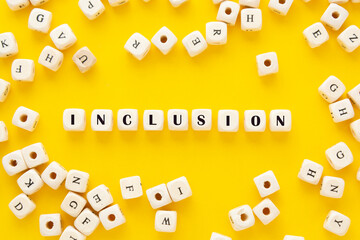 Inclusion text yellow background. Inclusive social concept. Wooden blocks, top view.