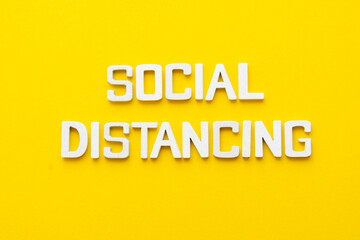 Social distancing word wooden letters yellow background.