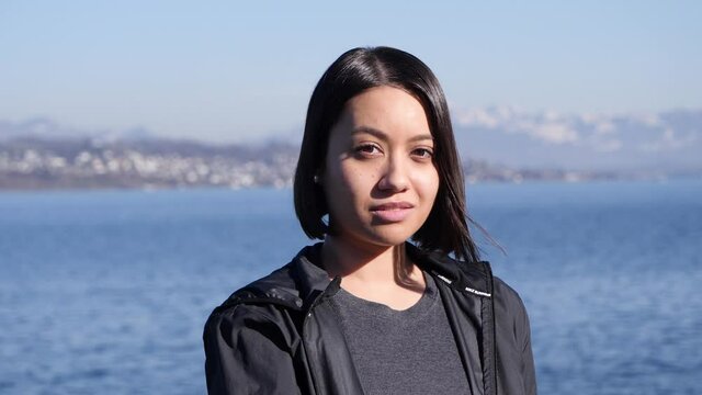 Portrait of a southeast Asian woman in a European lake and mountain setting.