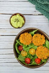 Rucola salad with cherry tomatoes, sesame seeds, falafel and guacamole