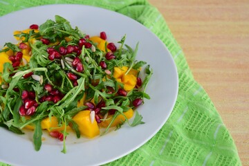 Arugula salad with mango and pomegranate served with Vinaigrette dressing