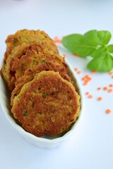 Patties of red lentils with basil leaf on white background