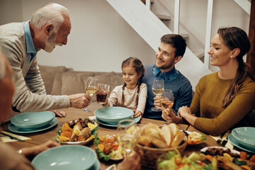 Happy multi-generation family toasting at dining table.