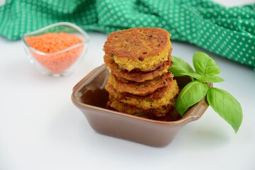 Patties of red lentils with basil leaf on white background