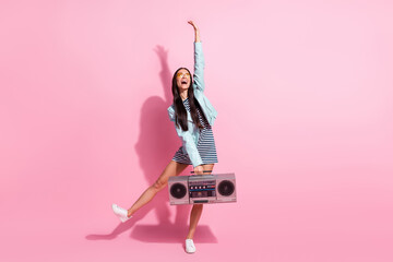 Full length photo of cute shiny young lady wear striped dress dancing holding boombox isolated pink...