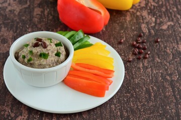 Red mung bean hummus or Adzuki bean dip with bell pepper sticks on wooden background