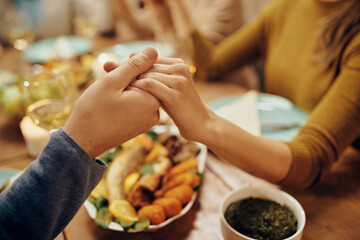 Close-up of couple saying grace before a meal at dining table.