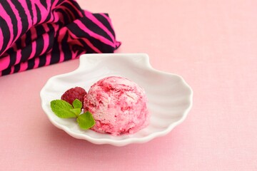 One scoop of raspberry ice cream with mint leaf. Pink background