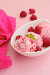 Scoops of raspberry ice cream in a bowl garnish with mint leaves. Summer dessert