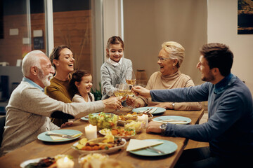 Fototapeta na wymiar cheerful extended family toasting during dinner at dining table.