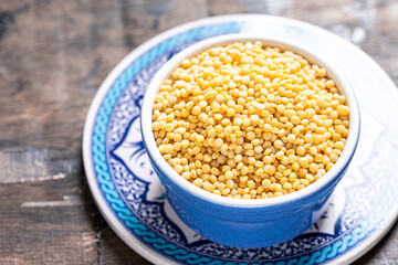 Dry ptitim close-up. Toasted pasta ptitim (petit plomb or Israeli couscous)  on a wooden background.