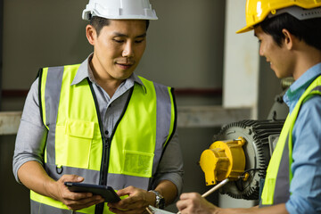 Senior and junior engineers talking together with intimated manner beside the machine in factory....