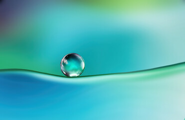 Beautiful clean bright drop of water on smooth surface in blue and turquoise colors, macro. Creative image of beauty of environment and nature.
