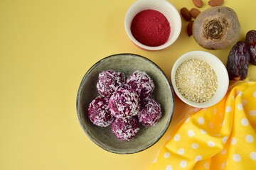 Beetroot quinoa date almond coconut energy balls on yellow background