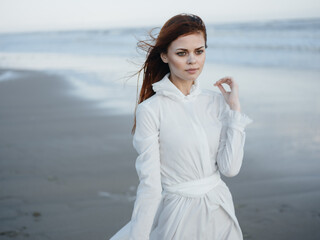 Woman in white dress near the ocean barefoot portrait