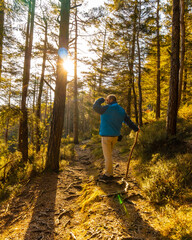 A young man looking at the sun with a blue jacket on a trek through the woods one afternoon at sunset. Artikutza forest in Oiartzun, Gipuzkoa. Basque Country