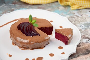 Homemade gluten free vegan beetroot chocolate cake with almond butter topping garnish with hemp seeds, mint leaf and sliced beetroot. 