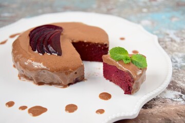 Homemade gluten free vegan beetroot chocolate cake with almond butter topping garnish with hemp seeds, mint leaf and sliced beetroot. 