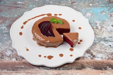 Homemade gluten free vegan beetroot chocolate cake with almond butter topping garnish with hemp seeds, mint leaf and sliced beetroot. 