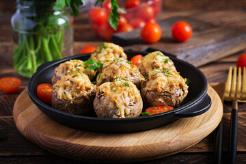 Baked mushrooms stuffed with chicken minced meat, cheese and herbs on a wooden background