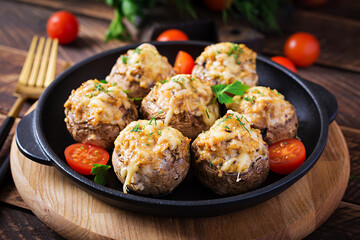 Baked mushrooms stuffed with chicken minced meat, cheese and herbs on a wooden background