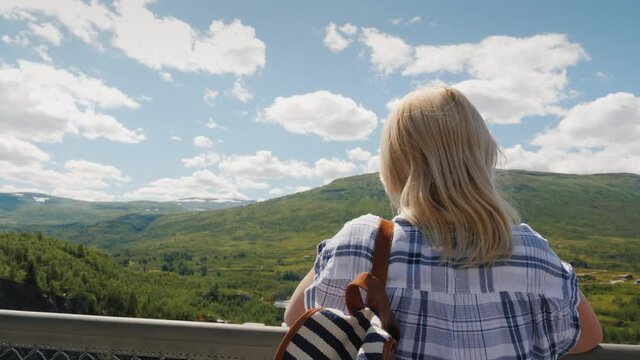 Satisfied tourist looks at the majestic waterfall of Woringsfossen in Norway. Impressive beauty of Scandinavian nature
