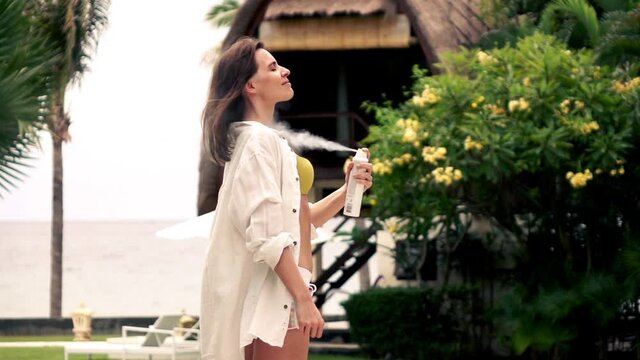 Young, pretty woman applying deodorant during summer holiday, super slow motion
