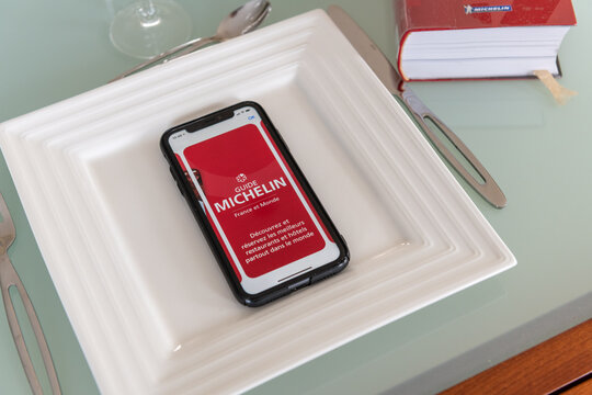 Paris, France - February 15, 2021 - Red Michelin guide book and smartphone application, which reviews restaurants.