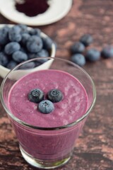 Fresh blueberry smoothie in a glass on wooden background. Selective focus