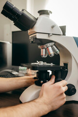 A doctor sits in a laboratory and makes a study under a microscope