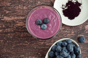 Obraz na płótnie Canvas Fresh blueberry smoothie in a glass on wooden background. Flat lay