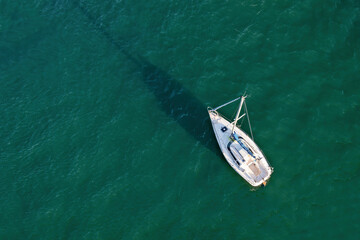 Aerial drone view of a sailing boat on emerald water..