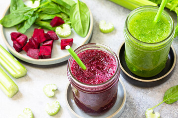 Vegan diet and nutrition, healthy detox, vegetarian concepts drinks. Beet smoothie and Green smoothie celery and spinach on a gray stone countertop.