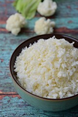 Cauliflower rice on green wooden background, selective focus